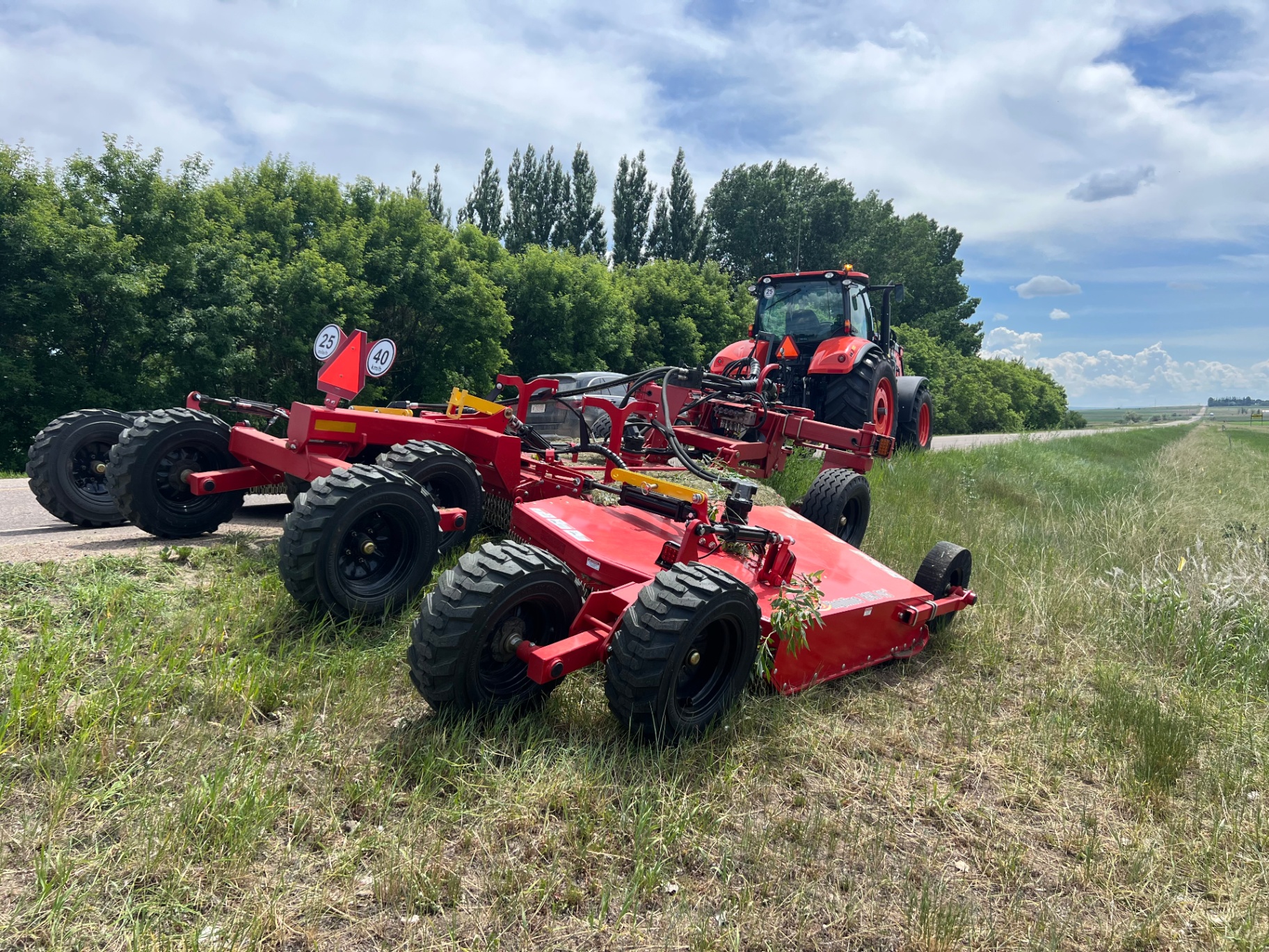 Avara tractor with batwing flail mower performing roadside vegetation control along an oil and gas lease access route